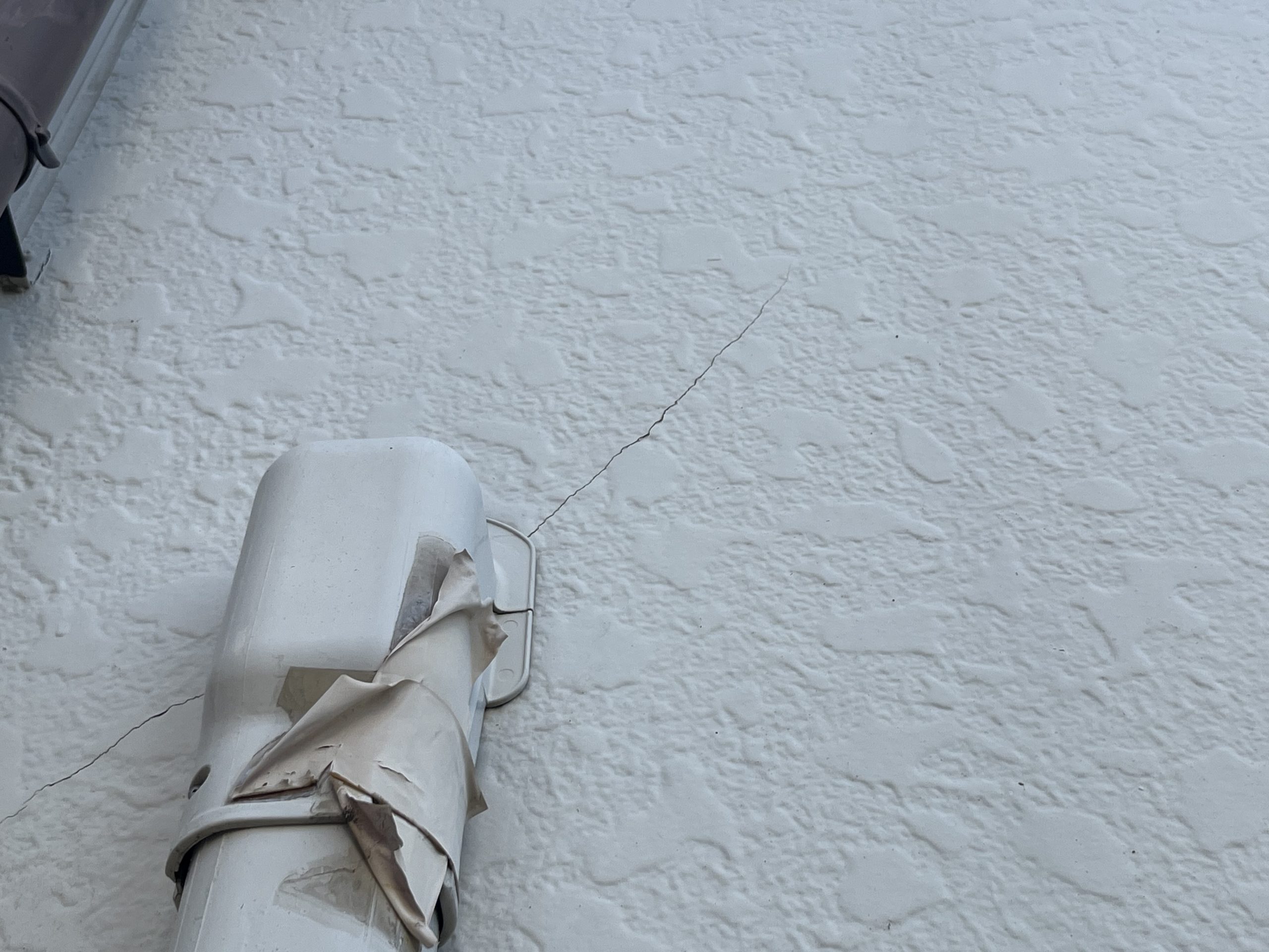 クーラーホースカバーが接している外壁部分に発生したひび割れ。外壁補修が必要な劣化サイン